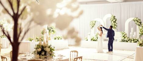 A wedding reception with round tables, white floral arrangements, and a dance floor.