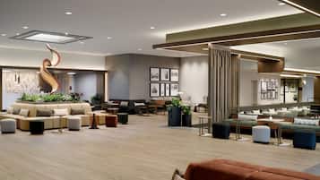 A modern hotel lobby with a curved sculpture, seating areas, and a large window.