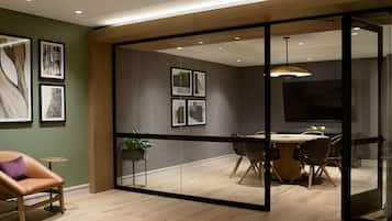 A modern dining area with a glass partition, wooden flooring, and contemporary furniture.
