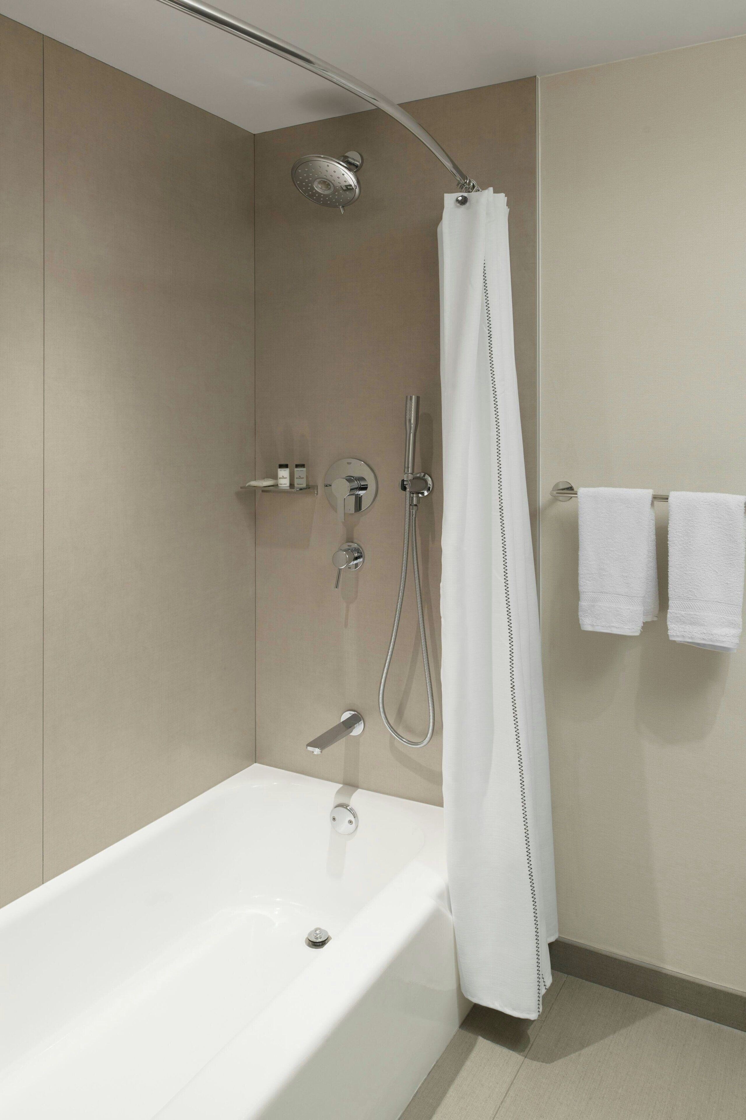 Ein modernes Badezimmer mit Badewanne, Dusche und Handtuchhalter.
