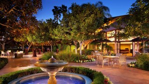 A well-lit outdoor area with a fountain, seating, and a building with a large window. - Sheraton Park Hotel at the Anaheim Resort (Anaheim)