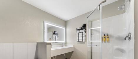 A modern bathroom with a bathtub, a glass-enclosed shower, and a vanity with a mirror.