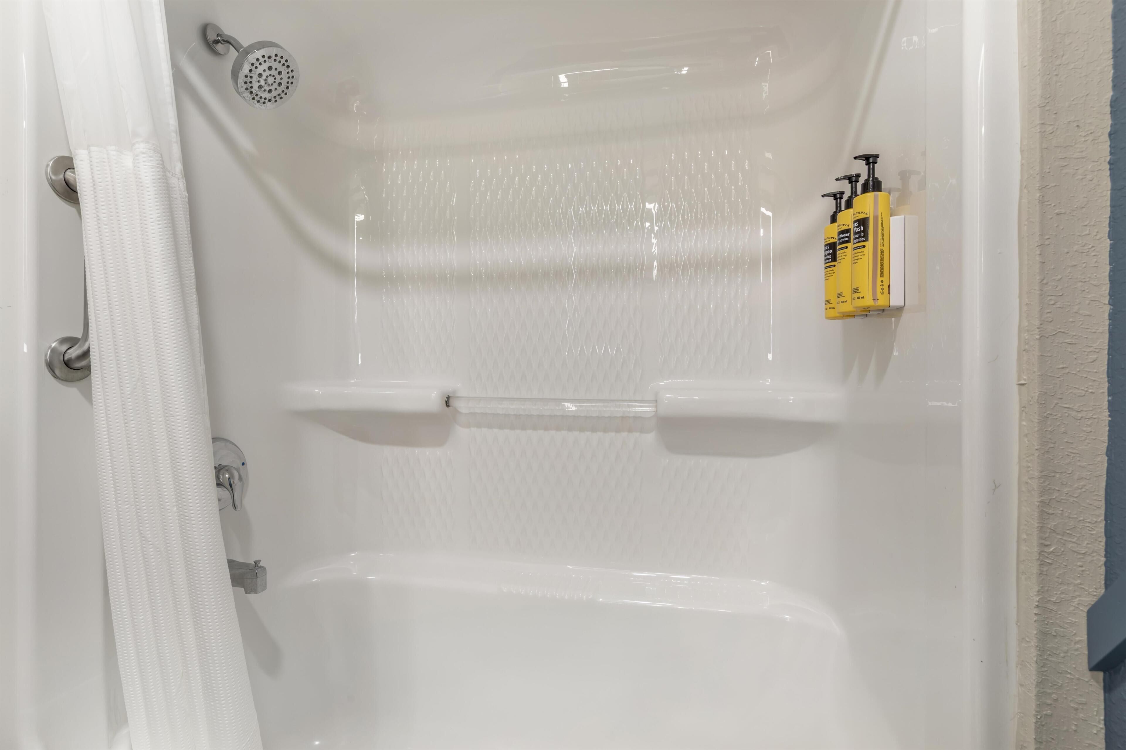 Une baignoire équipée d’un pommeau de douche, d’un porte-serviettes et d’un distributeur de savon.