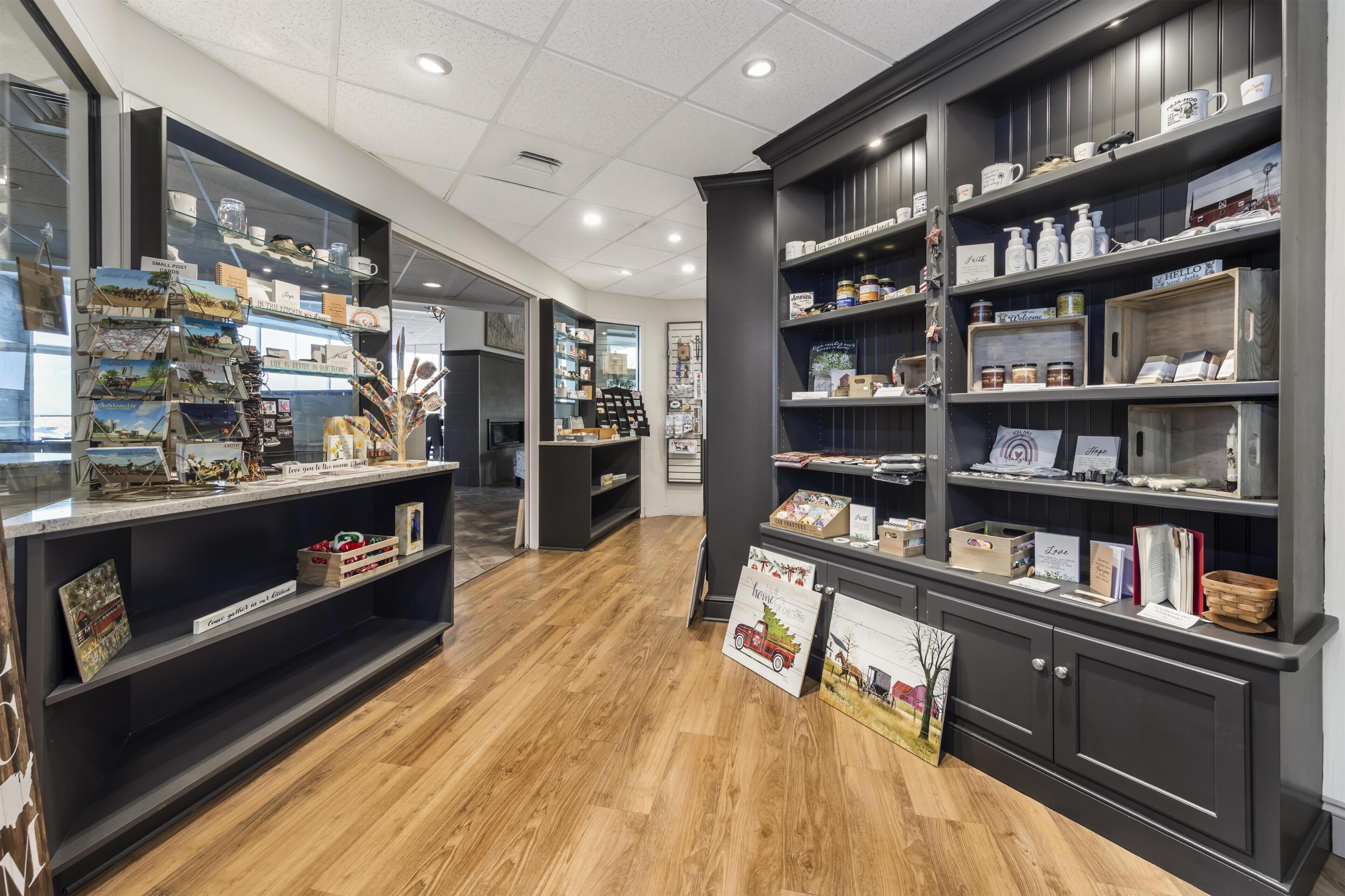 A modern interior with wooden flooring, dark shelving units, and various items displayed on shelves.