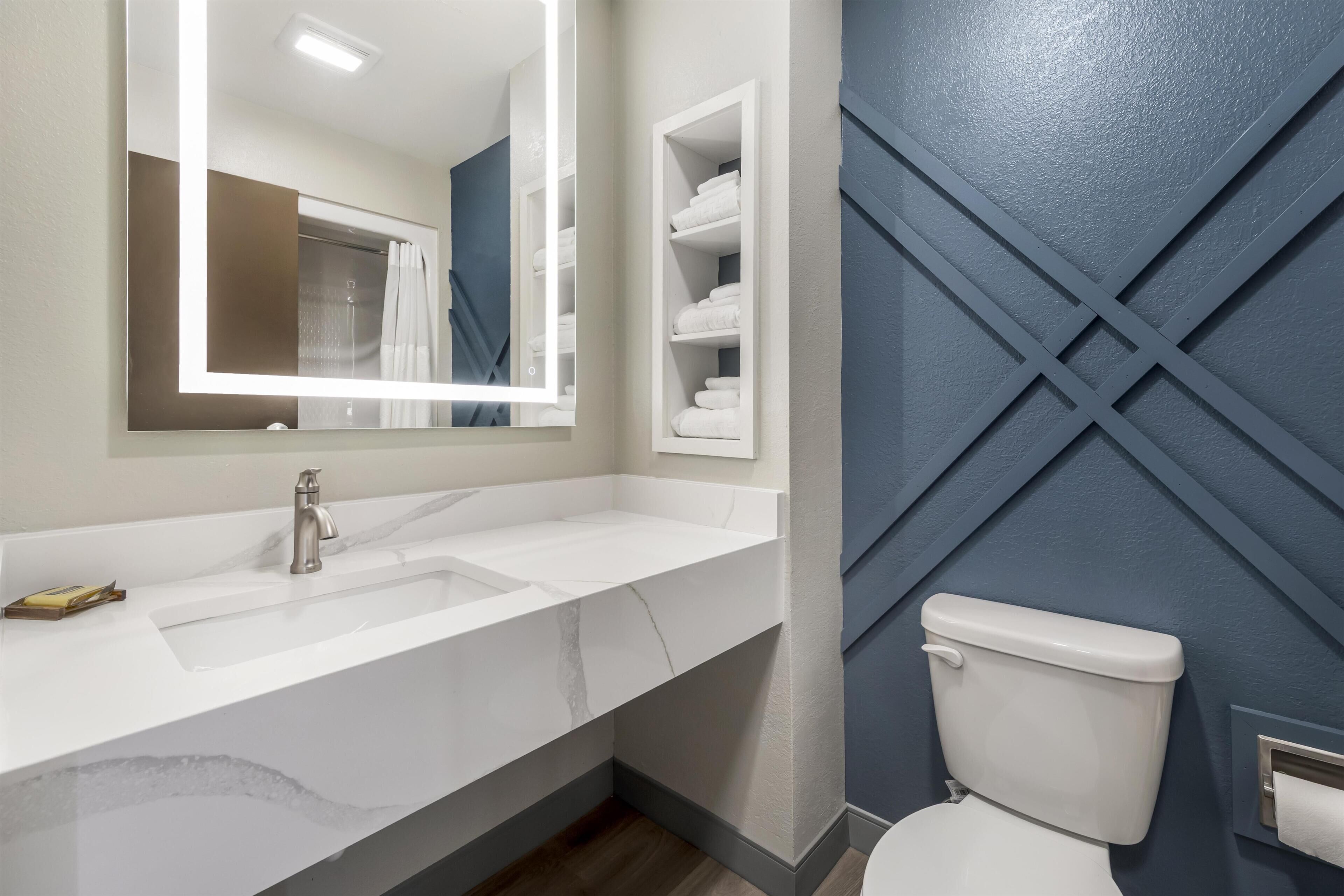 Un baño con un lavabo blanco, un espejo, un inodoro y un perchero para toallas.