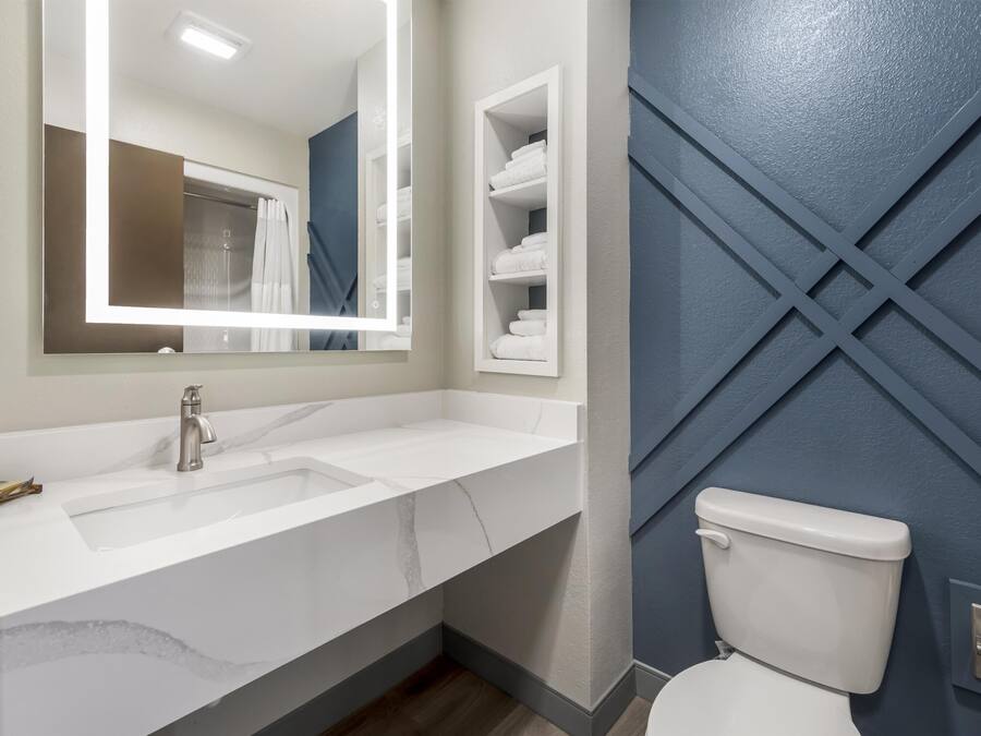 Un baño con un lavabo blanco, un espejo, un inodoro y un perchero para toallas.