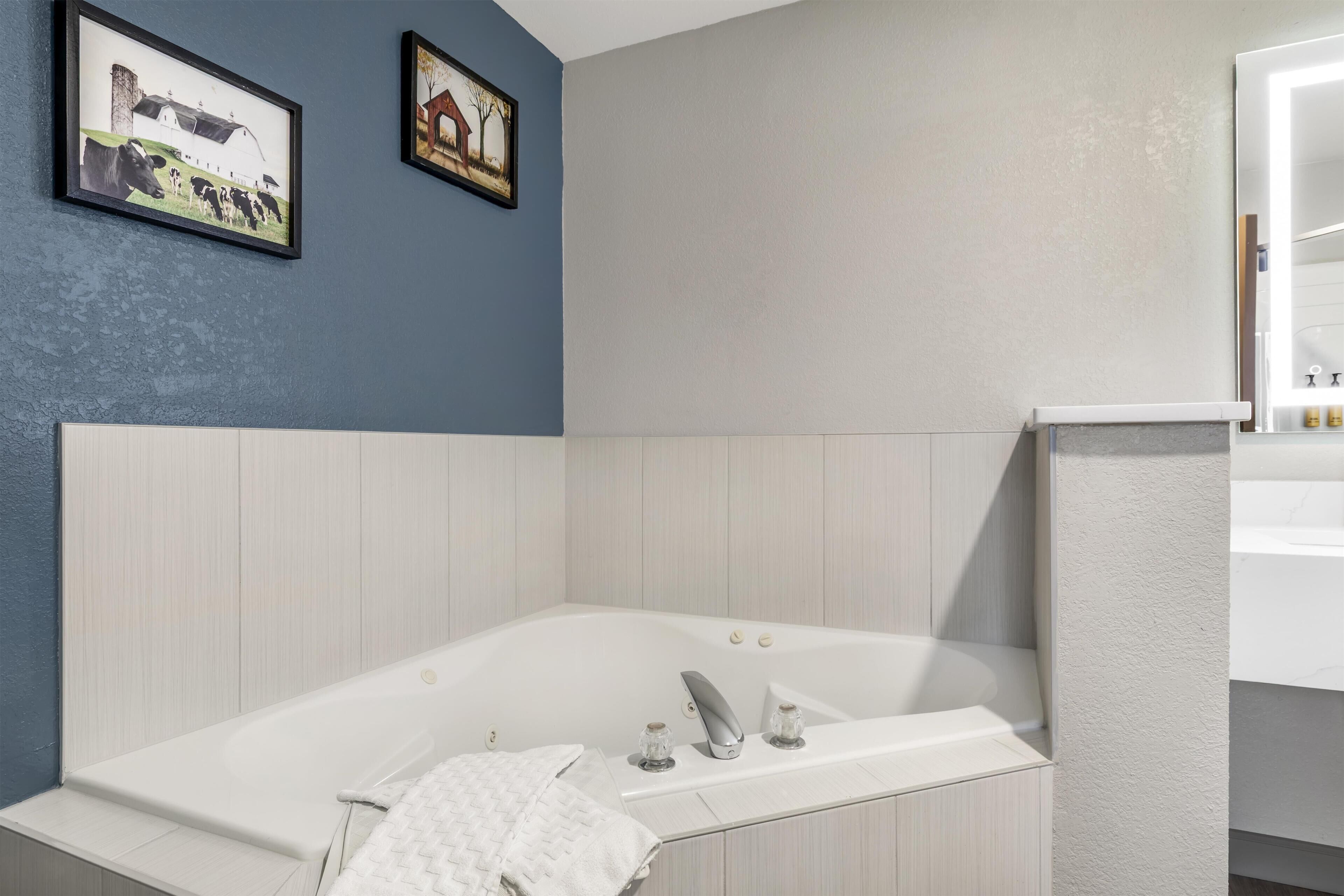 A modern bathroom with a freestanding bathtub, a vanity with a mirror, and two framed pictures on the wall.