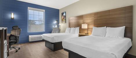 A hotel room with two beds, a desk, a chair, and a large window.