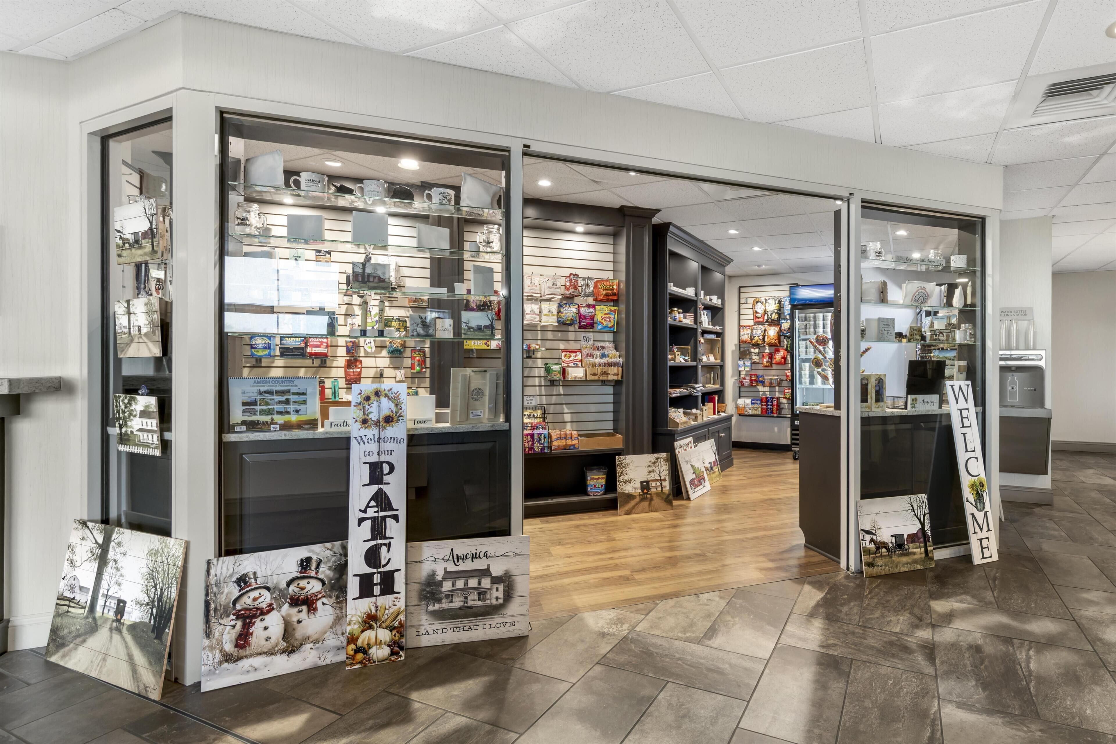 Een winkel met glazen etalages, planken vol diverse artikelen, en een 'WELCOME'-bord.