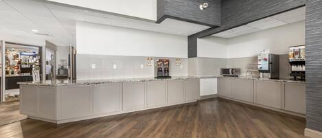A modern kitchen with a central island, built-in appliances, and a wooden floor.