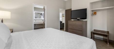 A hotel room with a bed, a television, a wardrobe, and a bench.