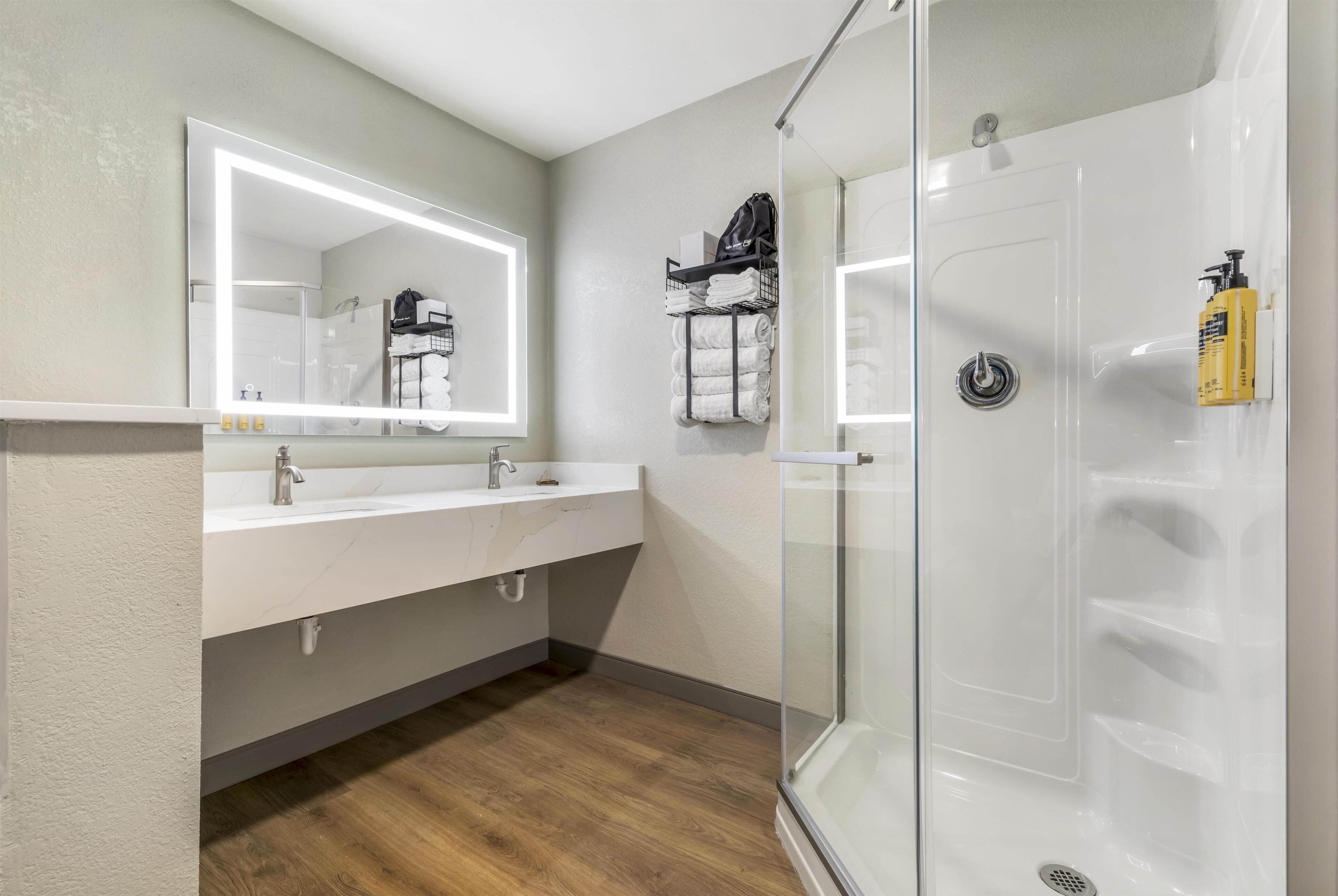 Une salle de bain moderne avec une douche à parois de verre, un meuble-lavabo avec un miroir et un porte-serviettes.