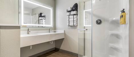 Une salle de bain moderne avec une douche à parois de verre, un meuble-lavabo avec un miroir et un porte-serviettes.