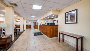 A hotel lobby with a reception desk, seating area, and a tiled floor.