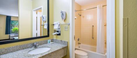 Baño con lavamanos de granito, espejo, toallero, secador de pelo y zona de ducha con bañera.