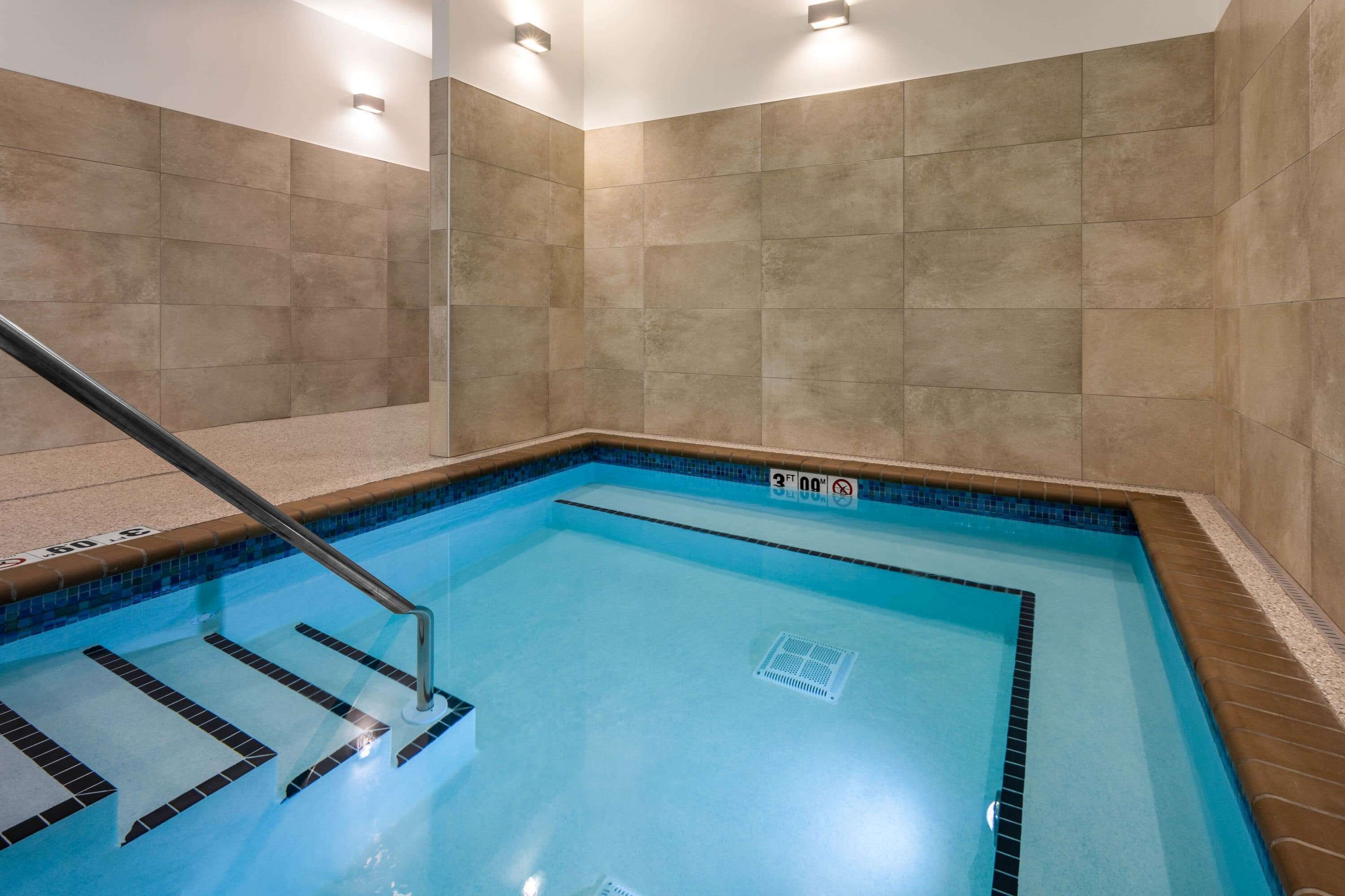 A swimming pool with a tiled border, a pool ladder, and a sign indicating a depth of 3 feet.