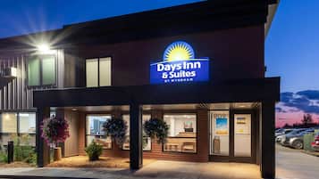 Edificio de Days Inn & Suites by Wyndham con un letrero llamativo, ventanas grandes y macetas colgantes de flores.