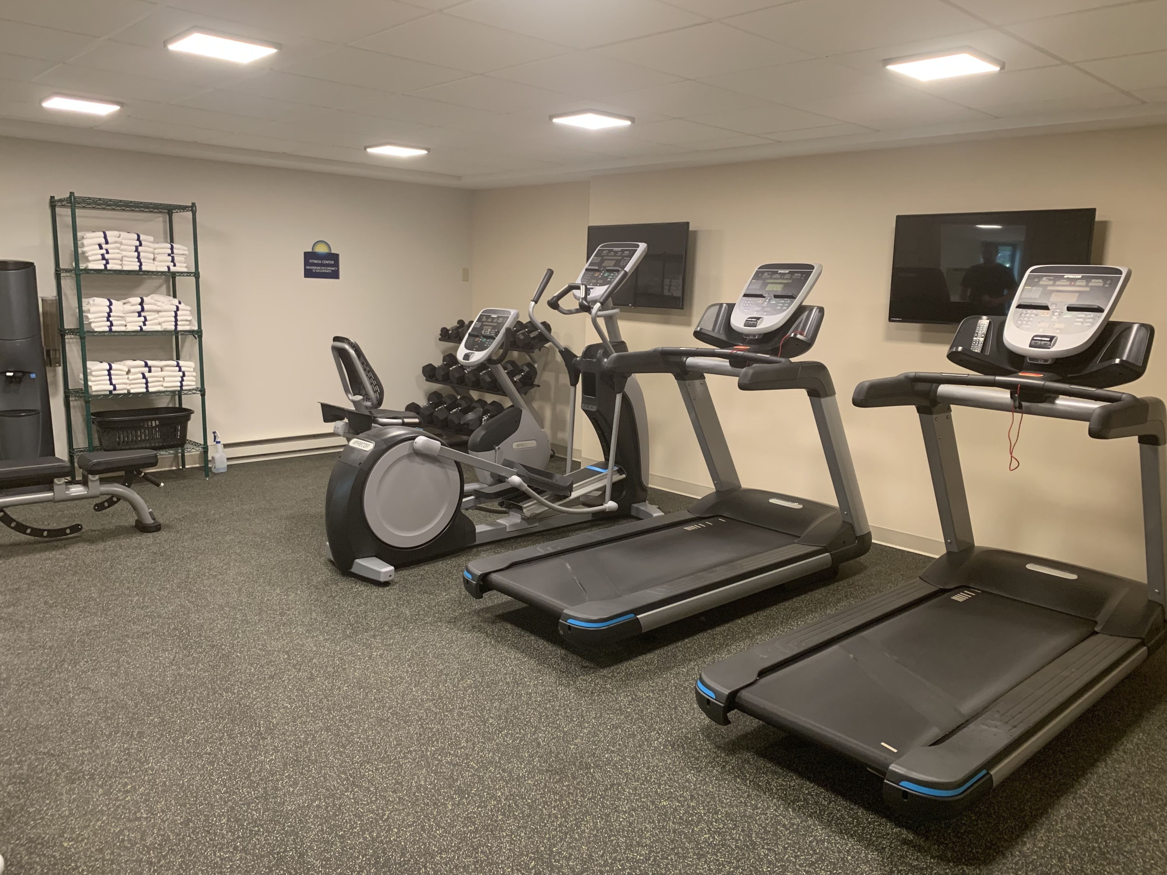 A fitness center with treadmills, an elliptical, and a weight bench.