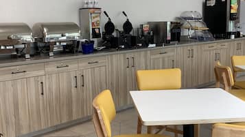 Una cocina equipada con una parrilla, plancha para waffles, cafetera y refrigerador.