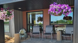 An outdoor seating area with four chairs and hanging flower baskets. - Days Inn & Suites by Wyndham Duluth by the Mall (Duluth)