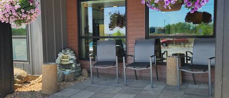 An outdoor seating area with four chairs and hanging flower baskets.