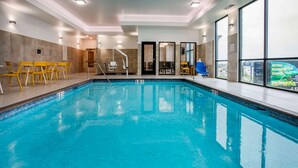 An indoor swimming pool with clear blue water, yellow chairs, and a sunbed. - Days Inn & Suites by Wyndham Duluth by the Mall (Duluth)