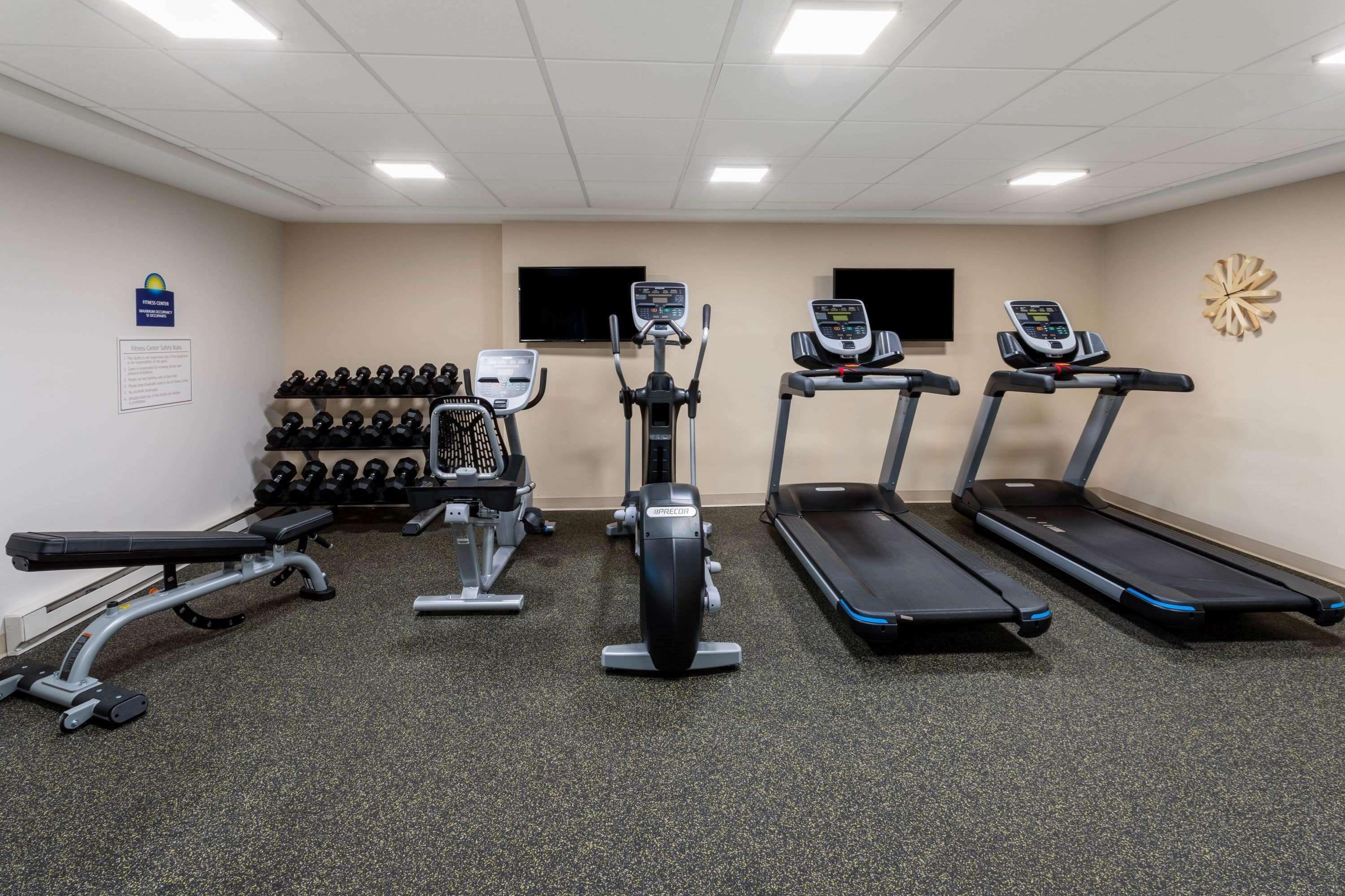 A gym with treadmills, an elliptical, and dumbbells.