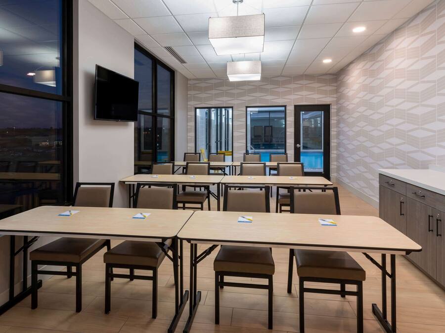 A conference room with tables, chairs, a TV, and a view of the outside.