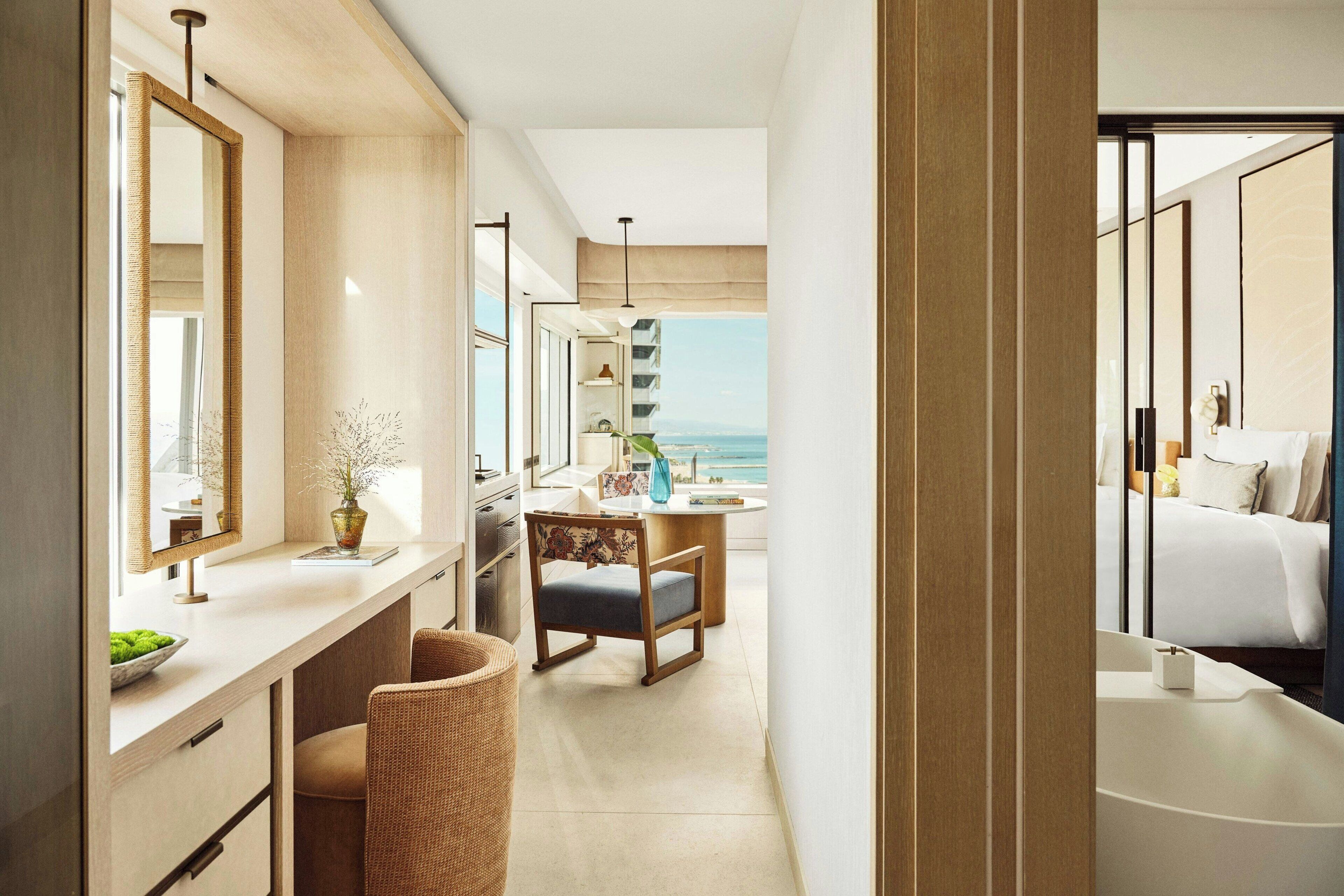 Habitación de hotel moderna con una cama grande, un escritorio con silla, una mesita y vistas al mar.