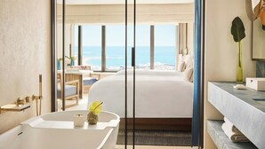A modern hotel room with a large bed, a bathtub, and a view of the beach. - Hotel Arts Barcelona (Barcelona)
