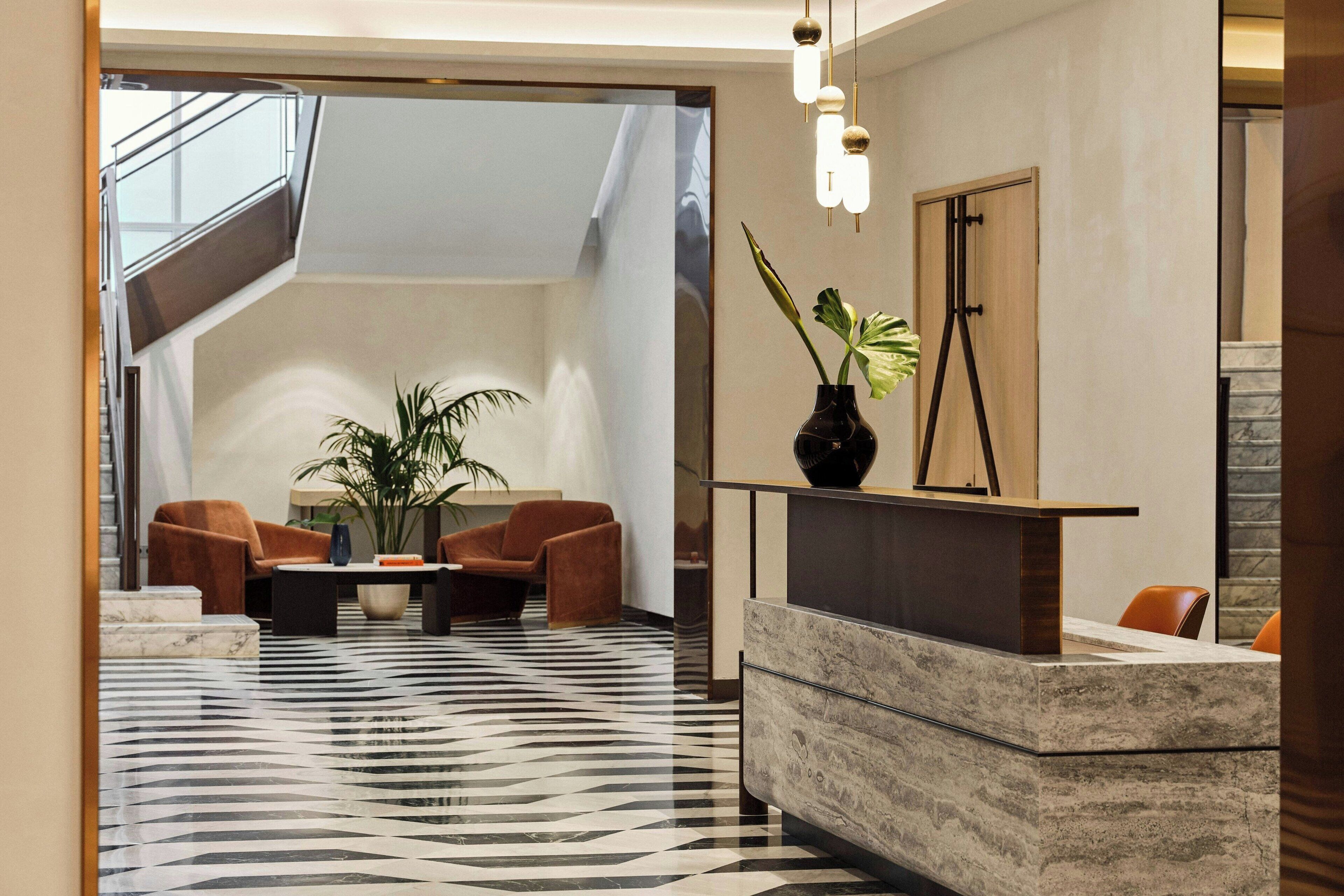 En moderne lobby med receptionsdisk, siddeområde og trappe.