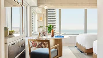 Une chambre d’hôtel moderne dotée d’une grande fenêtre, d’un lit, d’un bureau avec une chaise et offrant une vue sur la ville.