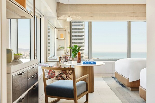 Un hotel moderno con una ventana grande, una cama, un escritorio con una silla y vistas a la ciudad.