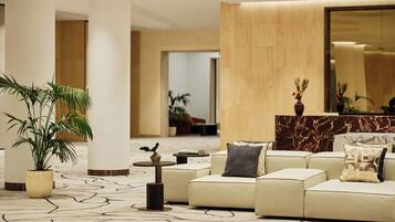 Un moderno vestíbulo con un sofá de color beige, un mostrador de recepción de mármol y un espejo grande.