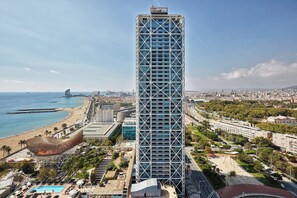Um hotel moderno com muitos andares, próximo a uma praia e ao horizonte urbano.