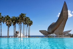 Piscina com palmeiras e uma escultura metálica singular.