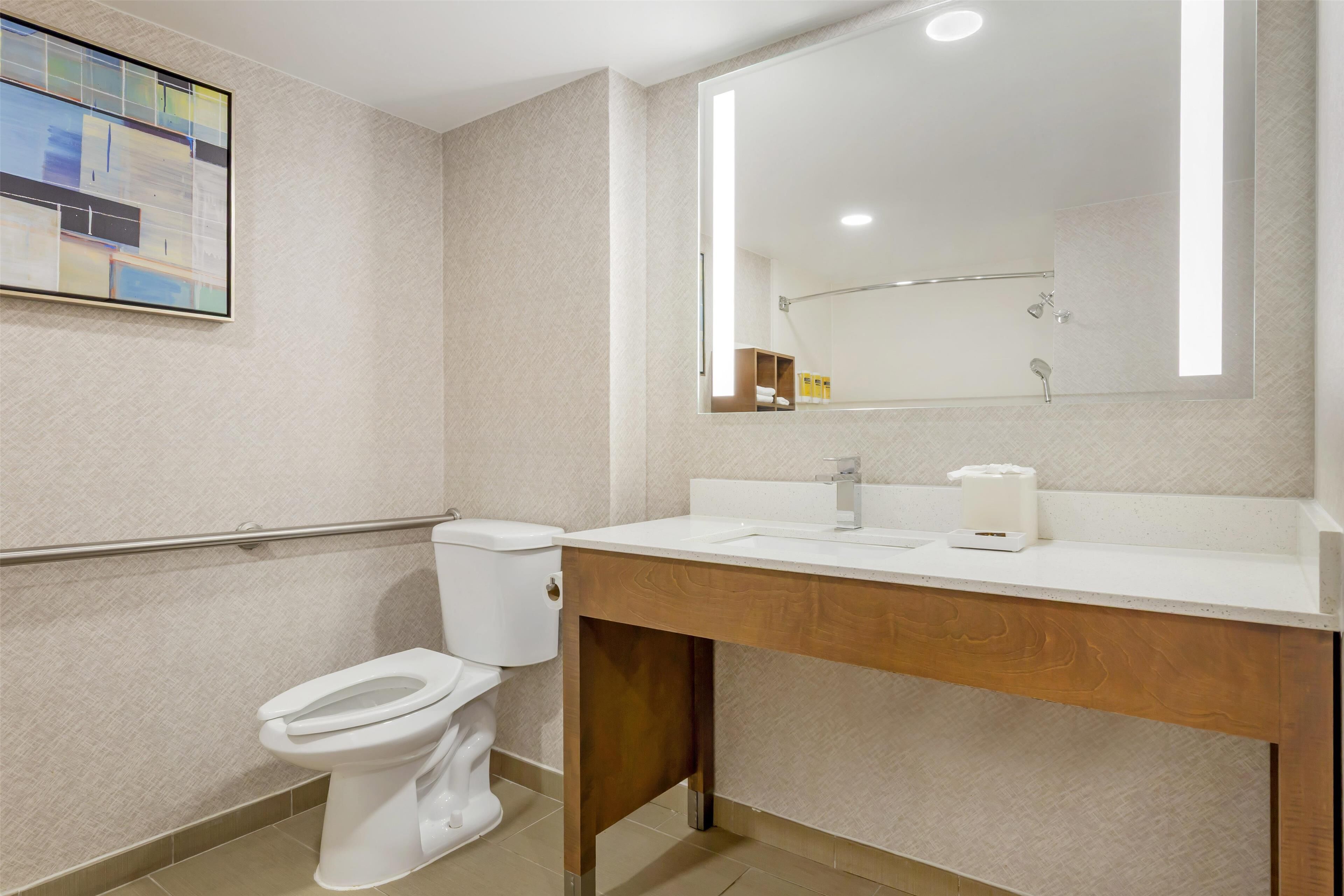 A modern bathroom with a toilet, sink, and mirror.