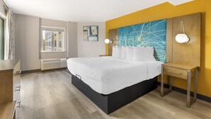 Moderni hotellihuone, jossa on suuri sänky, yöpöydät, ikkuna ja näkymä kaupunkiin.