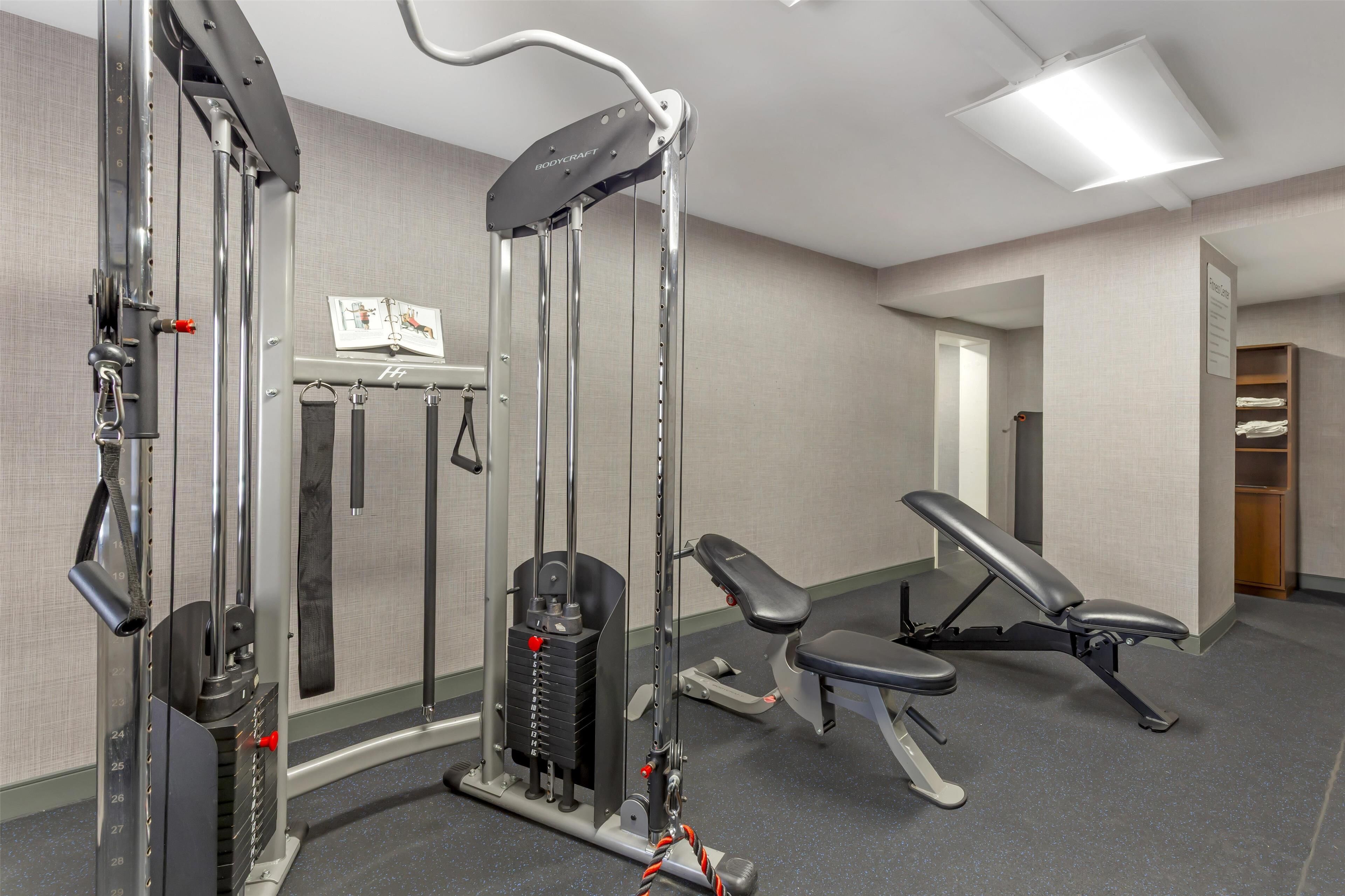 A gym with weightlifting equipment, a bench, and a mirror.