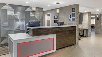 A reception area with a modern design, including a reception desk, a digital screen, and a wall with geometric patterns.