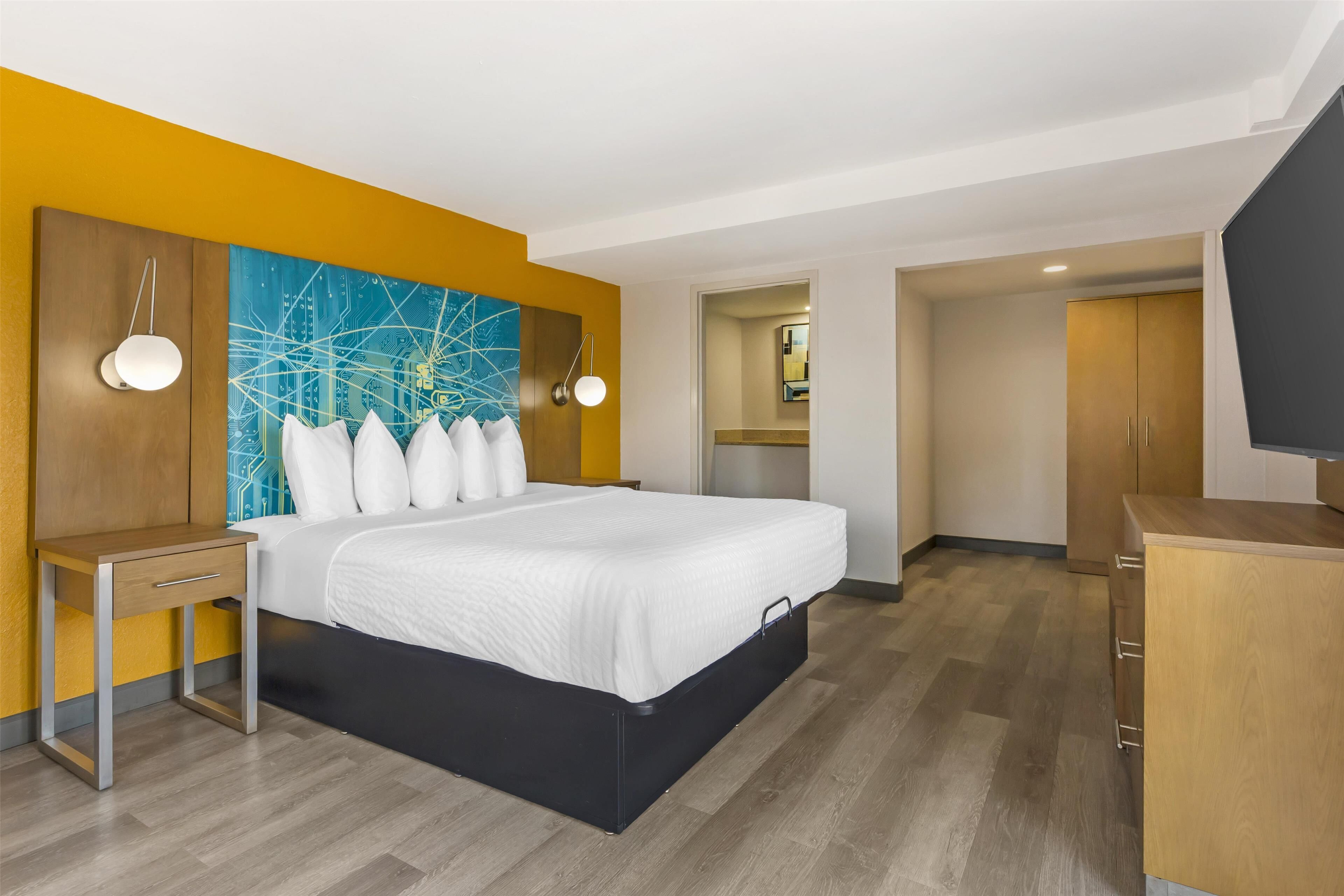 A hotel room with a bed, bedside table, and a TV.