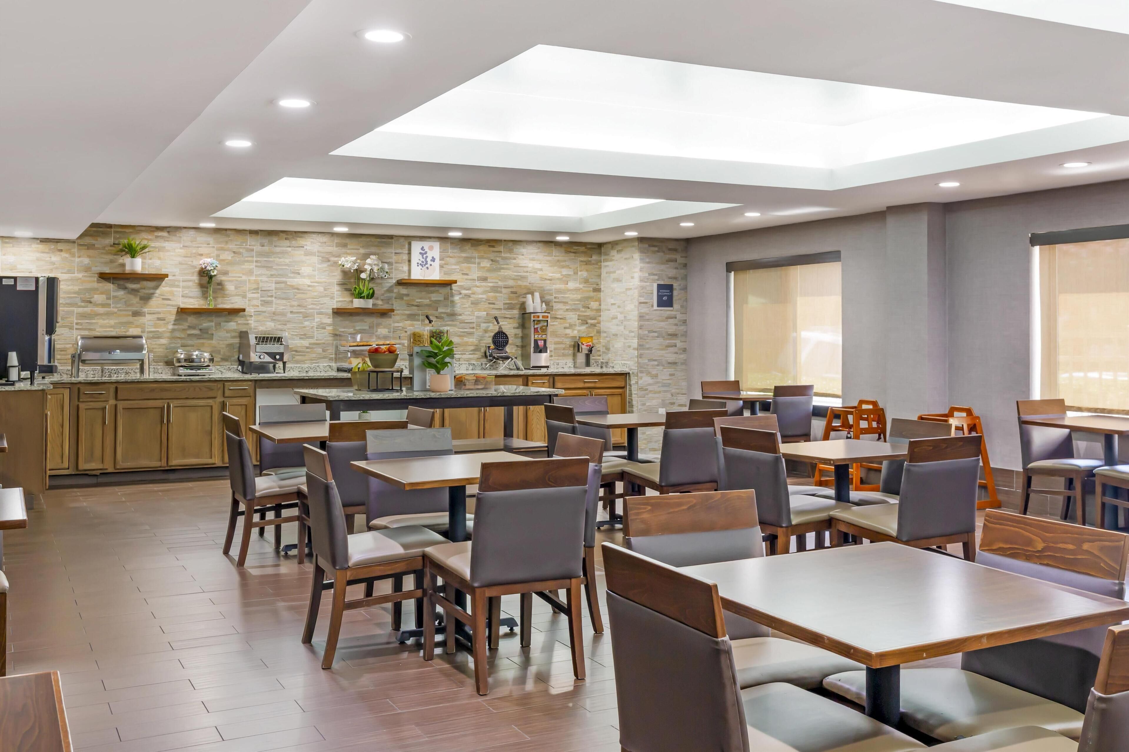 A modern restaurant with a central bar area, multiple dining tables, and chairs.