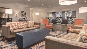 A hotel lobby with a seating area featuring sofas and armchairs, a coffee station, and decorative wall panels. - Radisson Hotel and Conference Center Fond du Lac (Fond du Lac)
