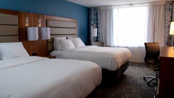 A hotel room with two beds, a desk, and a chair.