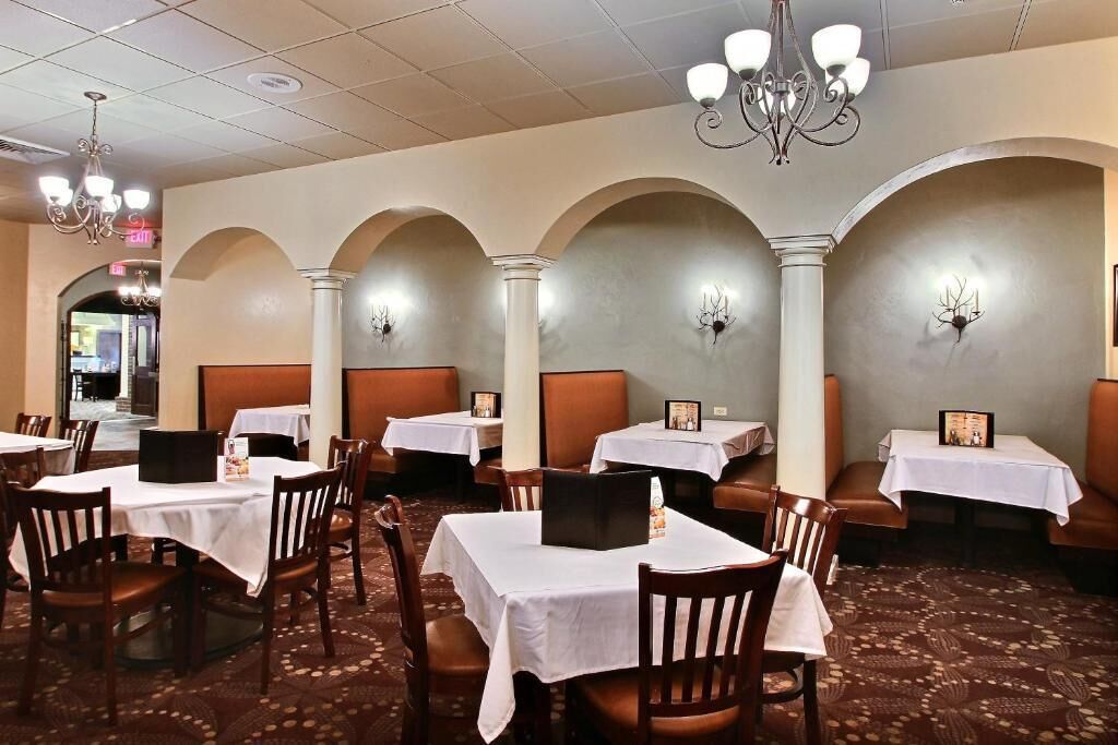 Un restaurante con mesas y sillas, candelabros y una alfombra estampada.