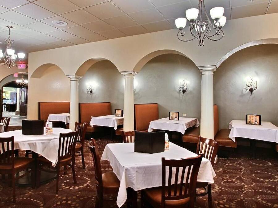 Un restaurante con mesas y sillas, candelabros y una alfombra estampada.