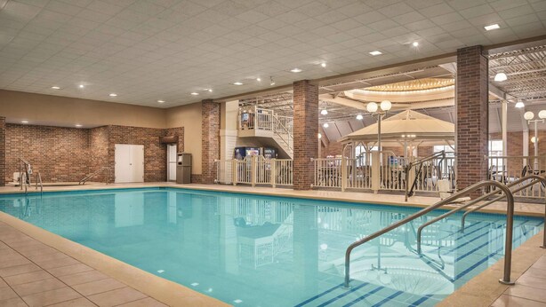 An indoor swimming pool with clear blue water, surrounded by tiled flooring and brick walls. - Radisson Hotel and Conference Center Fond du Lac (Fond du Lac)