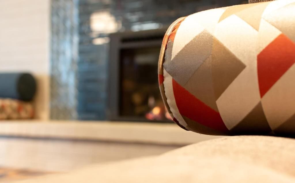 A close-up of a patterned object, possibly a cushion or decorative item, with a geometric design in red, white, and beige.