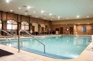 An indoor swimming pool with clear water, surrounded by brick walls and multiple seating areas. - Radisson Hotel and Conference Center Fond du Lac (Fond du Lac)