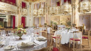 A luxurious banquet hall with ornate gold detailing, red curtains, and elegantly set tables. - Grand Hotel Bohemia (Prague)